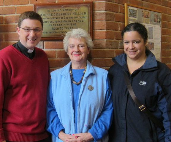 Reverend Peter Cornick, Barbara Hillier, and her daughter Jo Nash in front of the plaque which remembers  Barbara's great uncle Wilfred Herbert Hillier.