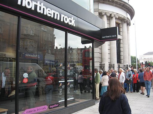 Customers queueing to retrieve their savings saving from Northern Rock during the banking collapse in 2007. By Alex Gunningham from London, Perfidious Albion (UK plc) (Northern Rock Customers, Golders Green.) [CC BY 2.0 (http://creativecommons.org/licenses/by/2.0)], via Wikimedia Commons